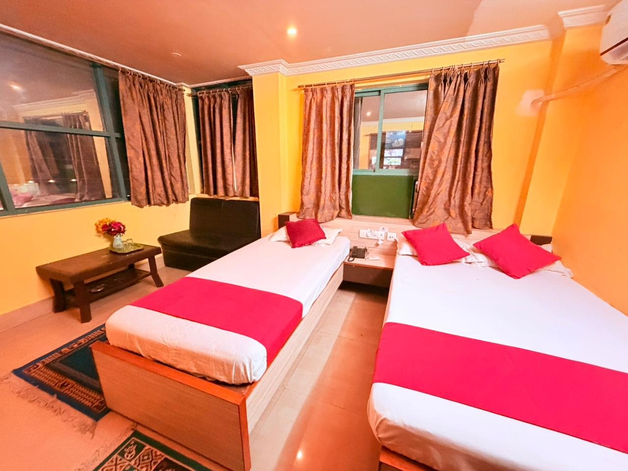 AC guest room with a double bed, curtained window and wall air conditioner