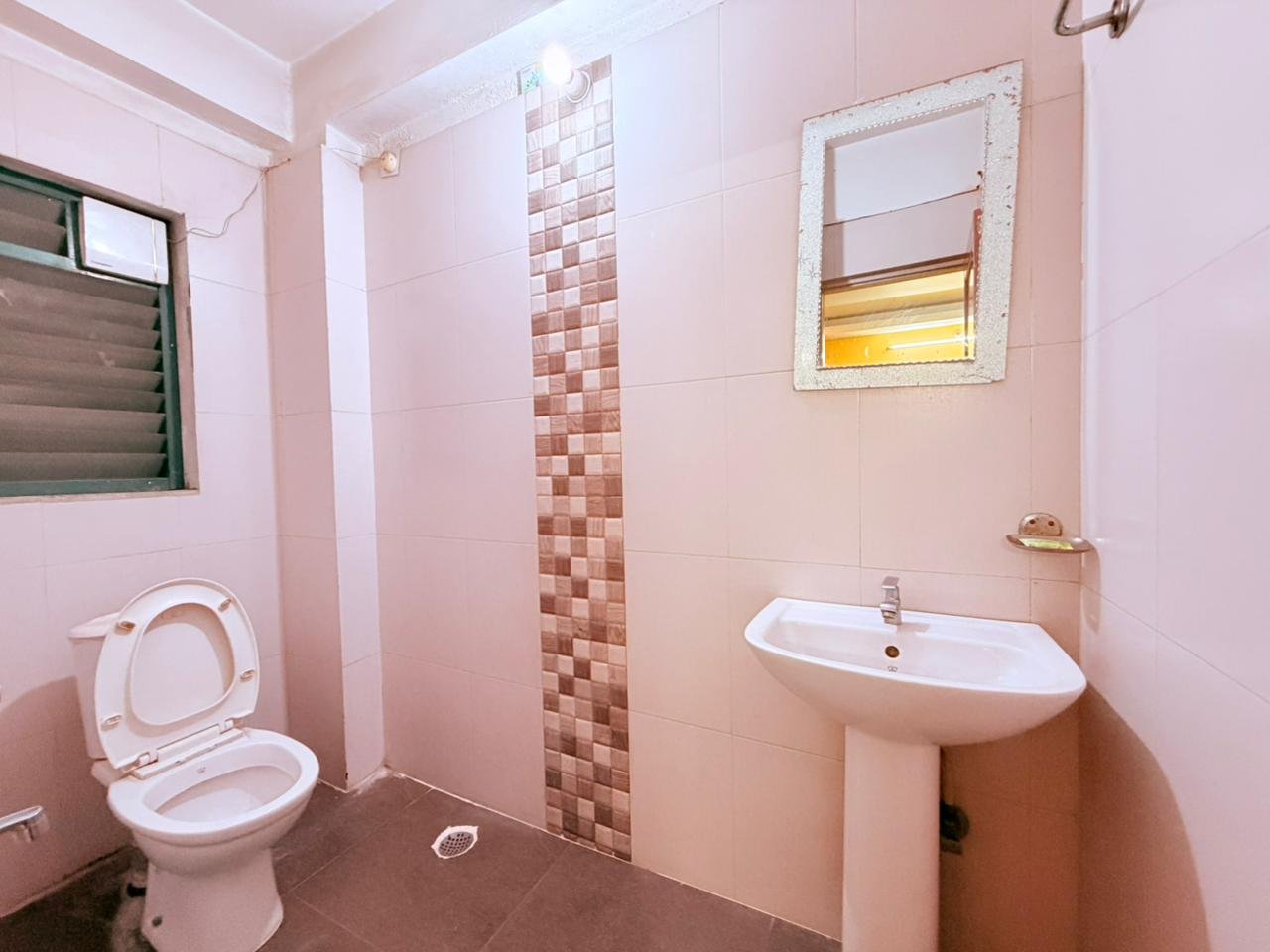Guest room bathroom with pedestal sink, mirror and tiled walls