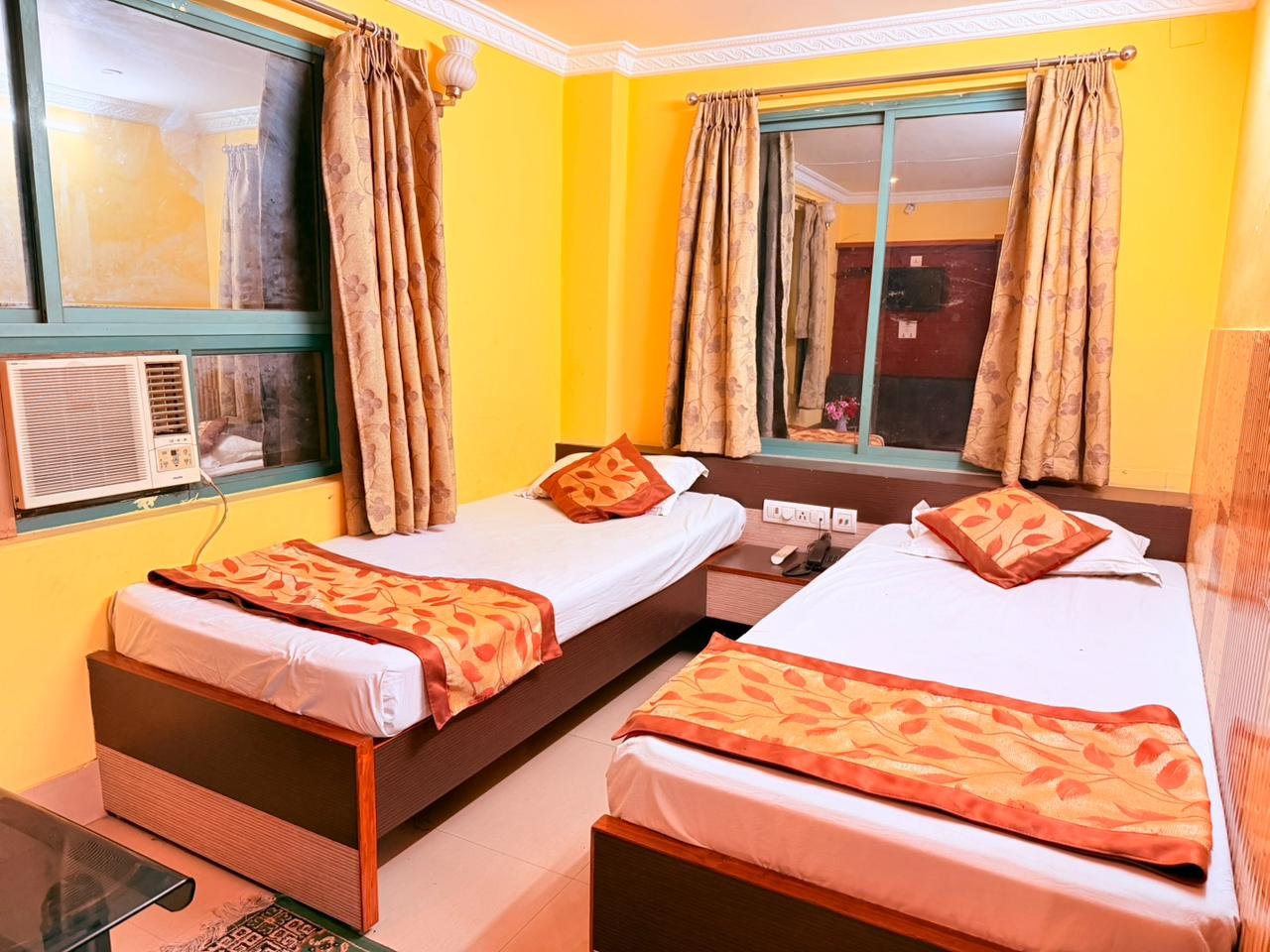 Twin-bed AC room with red cushions and patterned rugs